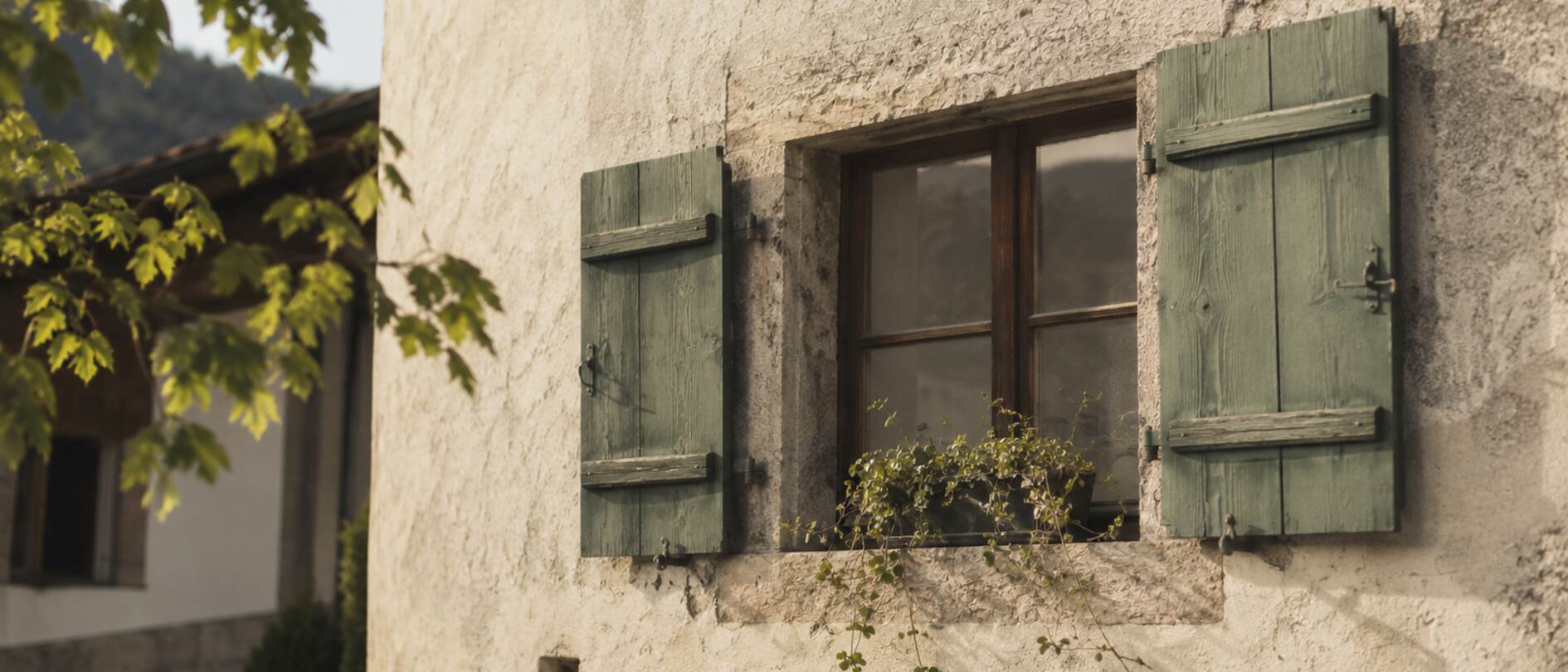 Fenster mit grünen Holzläden an einer verputzten Hausfassade
